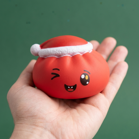Dumpling Squishy Czerwona Czapka Mikołaja w dłoni — porównanie rozmiaru